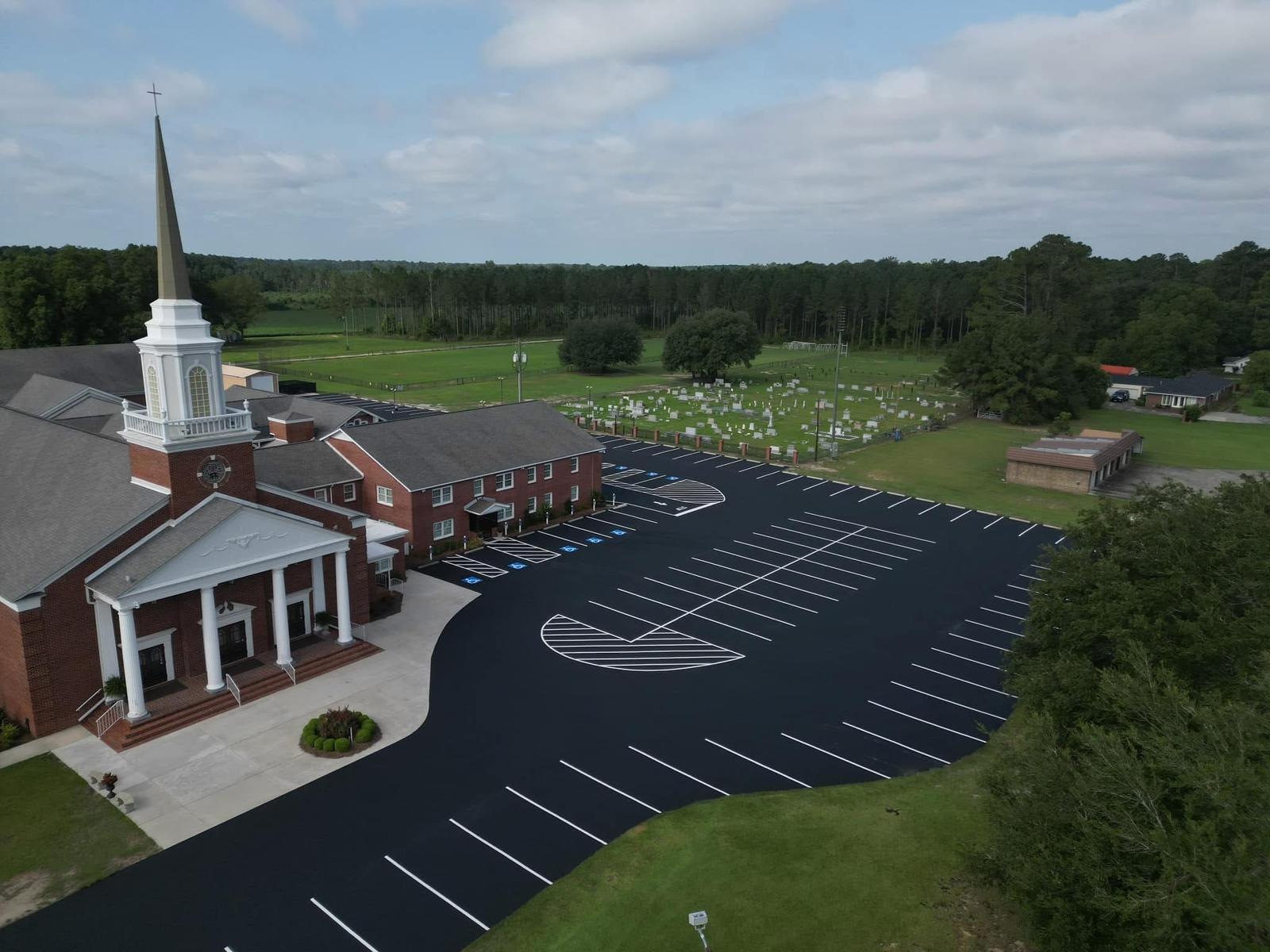 Aerial view of freshly seal-coated and line-striped church parking lot with crisp white markings and ADA-compliant handicap spaces